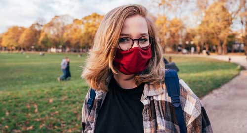 Student wearing a mask with a bookbag on their shoulder.